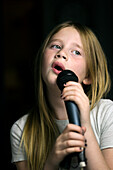 Mädchen hält Mikrofon und singt