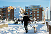 Mann geht mit Hund im Schnee spazieren