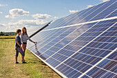 Boy and girl standing next to solar panels