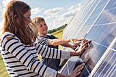Junge und Mädchen berühren Sonnenkollektoren
