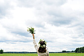 Woman wearing wreath standing in field