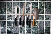 Kitchen knives against tiled wall