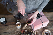 Frau gießt Glühwein ein und verpackt ein Geschenk