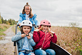 Mother pushing daughters in bicycle cart