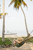 Woman lying on hammock on beach