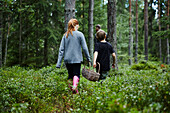 Mädchen und Junge tragen Korb im Wald
