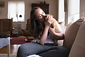 Young woman kissing dog at home