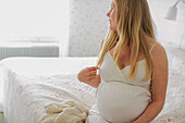 Pregnant woman sitting in bedroom