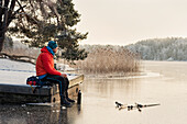 Mann ruht sich am zugefrorenen See aus