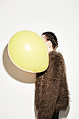 Woman with balloon covering face