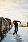 Mann entfernt mit Besen Schnee vom Gehweg