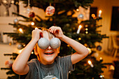Junge spielt mit Weihnachtsschmuck