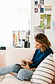 Woman sitting on sofa and using digital tablet