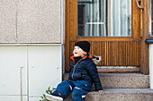 Boy sitting on door stairs