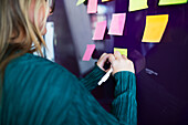 Woman writing on post-it