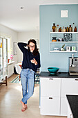 Frau telefoniert mit Smartphone in der Küche