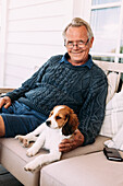 Mann sitzt auf Sofa mit Hund