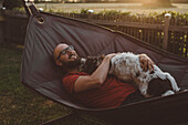 Mann entspannt in Hängematte mit Hund