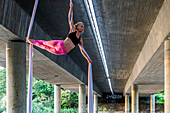 Woman doing acrobatics under concrete structure