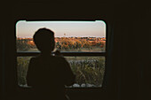 Silhouette eines Jungen, der durch ein Zugfenster schaut