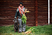 Woman with dog and freshly picked carrots