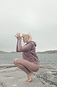 Young woman doing yoga by lake