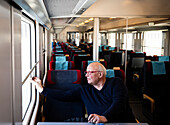 Älterer Mann schaut durch ein Zugfenster