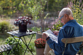 Man in garden reading newspaper