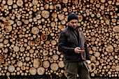 Mann vor einem Stapel Holzscheite stehend