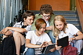 Teenagers on stairs using digital tablet