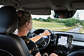 Frau am Steuer eines Autos mit GPS auf dem Armaturenbrett