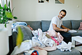 Man folding clothes on sofa