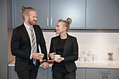 Coworkers standing in office kitchen