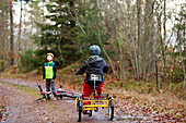 Boys cycling through forest