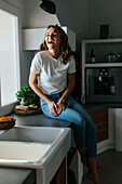 Glückliche Frau sitzt auf einem Küchenschrank