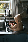 Baby having wash in sink