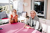 Smiling women sitting in front of house