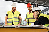 Workers reviewing blueprint at construction site