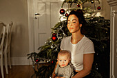 Mother with baby in front of Christmas tree