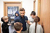 Teacher talking to children at school corridor