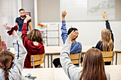 Kinder heben die Hände im Klassenzimmer