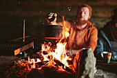 Man putting kettle on campfire