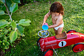 Kleines Mädchen schüttet Wasser über ein Auto