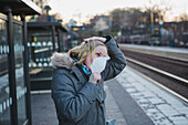 Frau mit Schutzmaske auf dem Bahnsteig