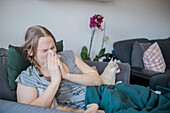 Woman on sofa sneezing