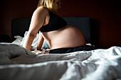 Pregnant woman sitting on bed