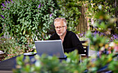 Mann mit Laptop im Garten