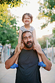 Father carrying toddler daughter on shoulders