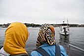 Women looking at boat on sea