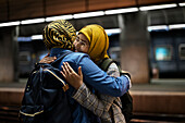 Freundinnen umarmen sich auf dem Bahnsteig